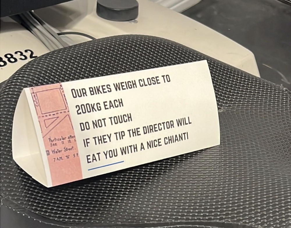 A sign on a bicycle seat reads: “Our bikes weigh close to 200kg each. Do not touch. If they tip the director will eat you with a nice Chianti.”