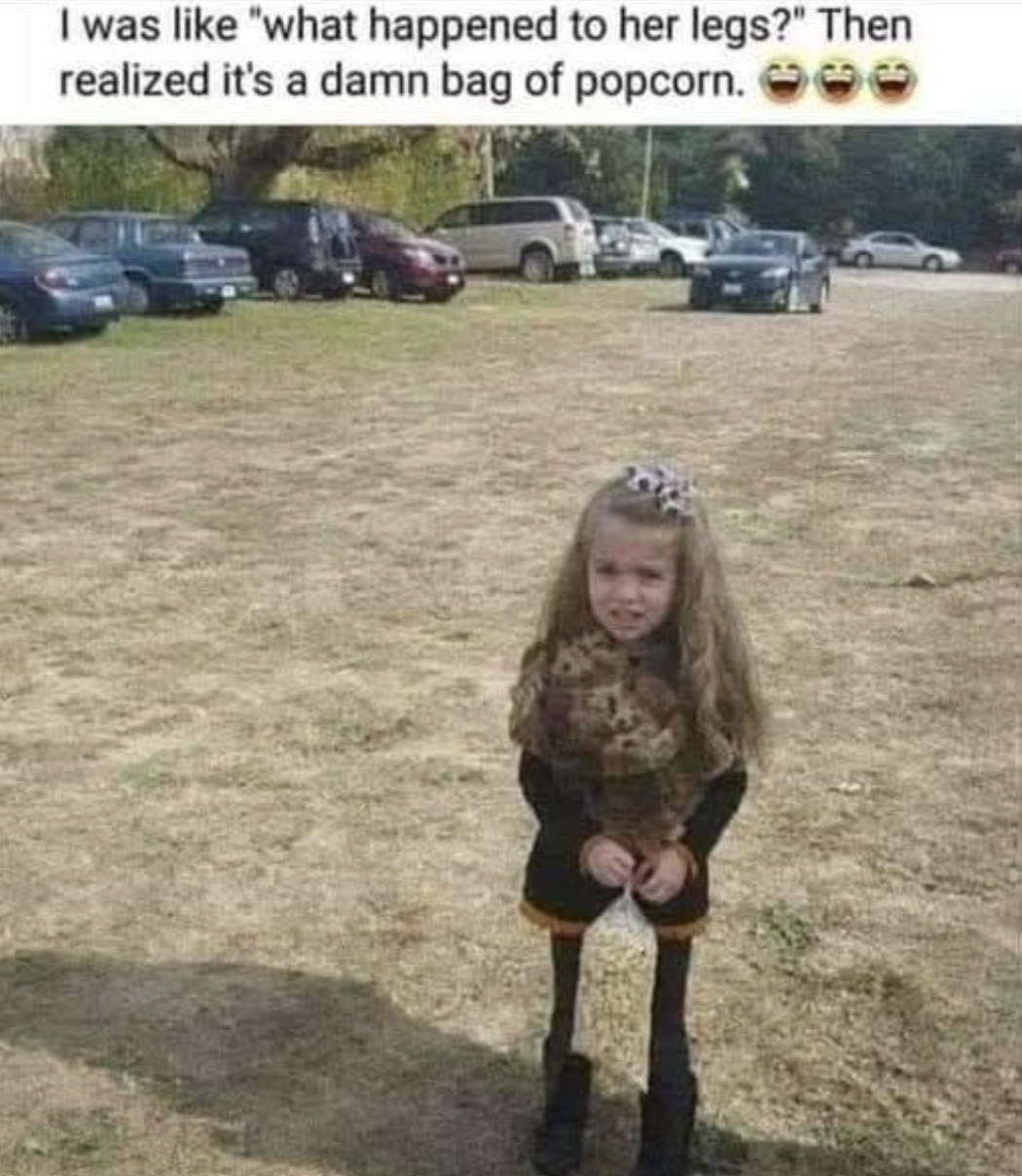 A young girl holding a bag of popcorn in front of her legs, creating an optical illusion that makes her legs appear very thin.
