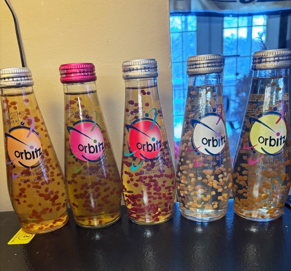 Five glass bottles of Orbitz drink, each filled with suspended edible gel spheres and labeled with the Orbitz logo.