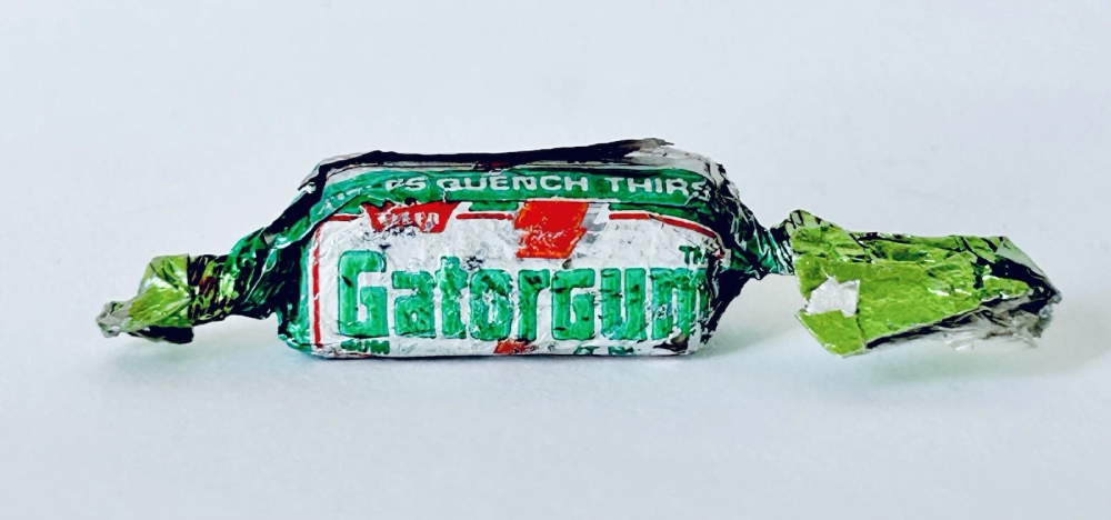 A piece of Gatorgum in a green and white foil wrapper.