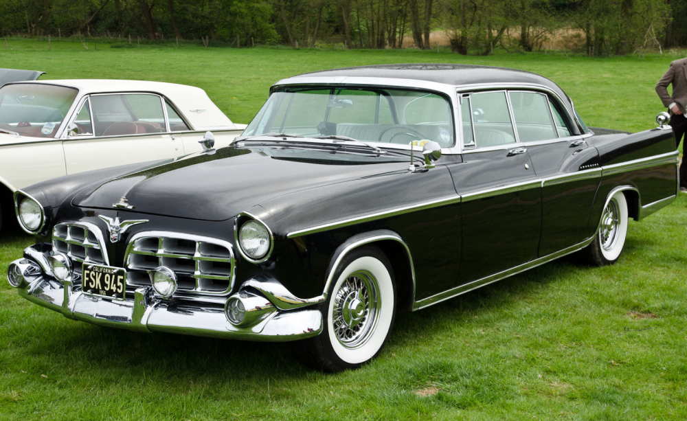 A black vintage Chrysler sedan with a prominent chrome grille and whitewall tires parked on a grass lawn.