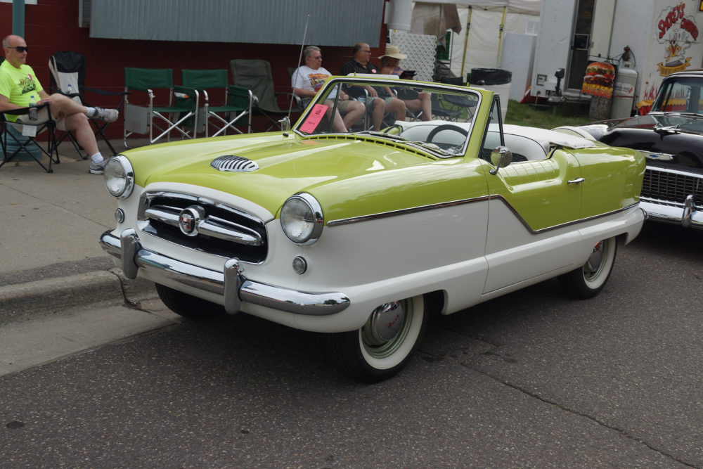 A vintage two-tone lime green and white convertible car parked on a street during a car show.