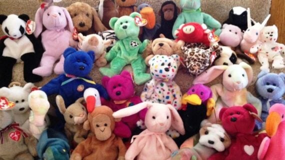 A large collection of colorful Ty Beanie Baby plush toys, including various animals like bears, rabbits, and monkeys, arranged together on a carpeted surface.
