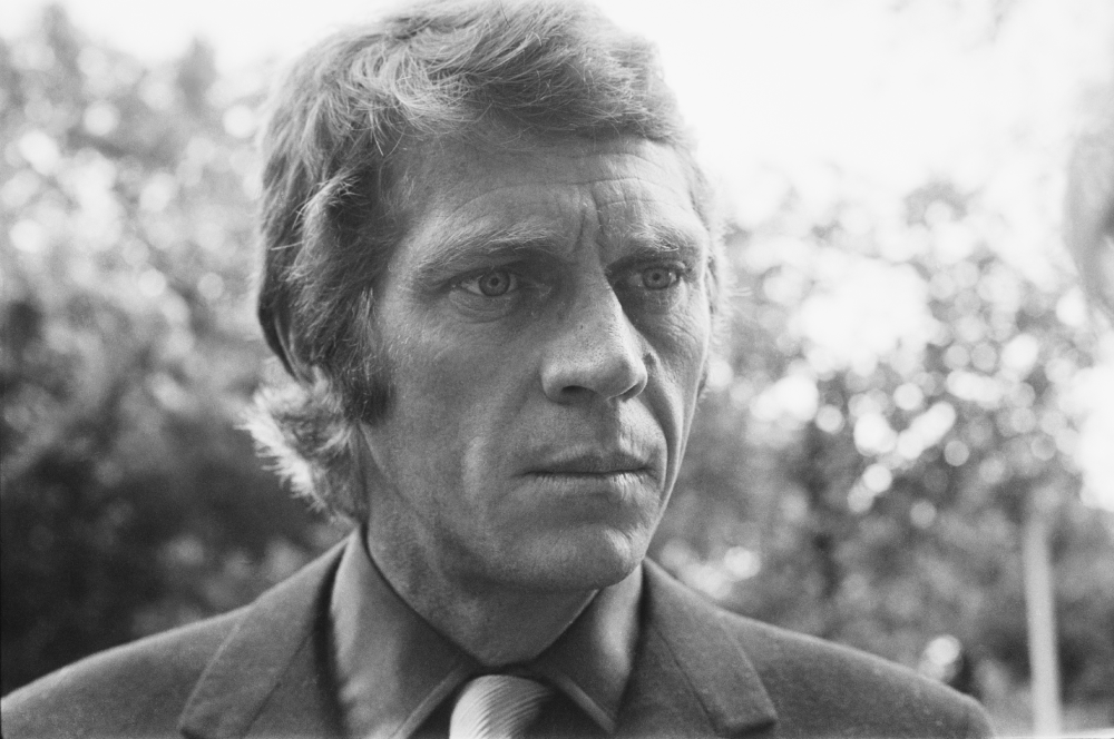 Black and white close-up portrait of actor Steve McQueen looking to the side.