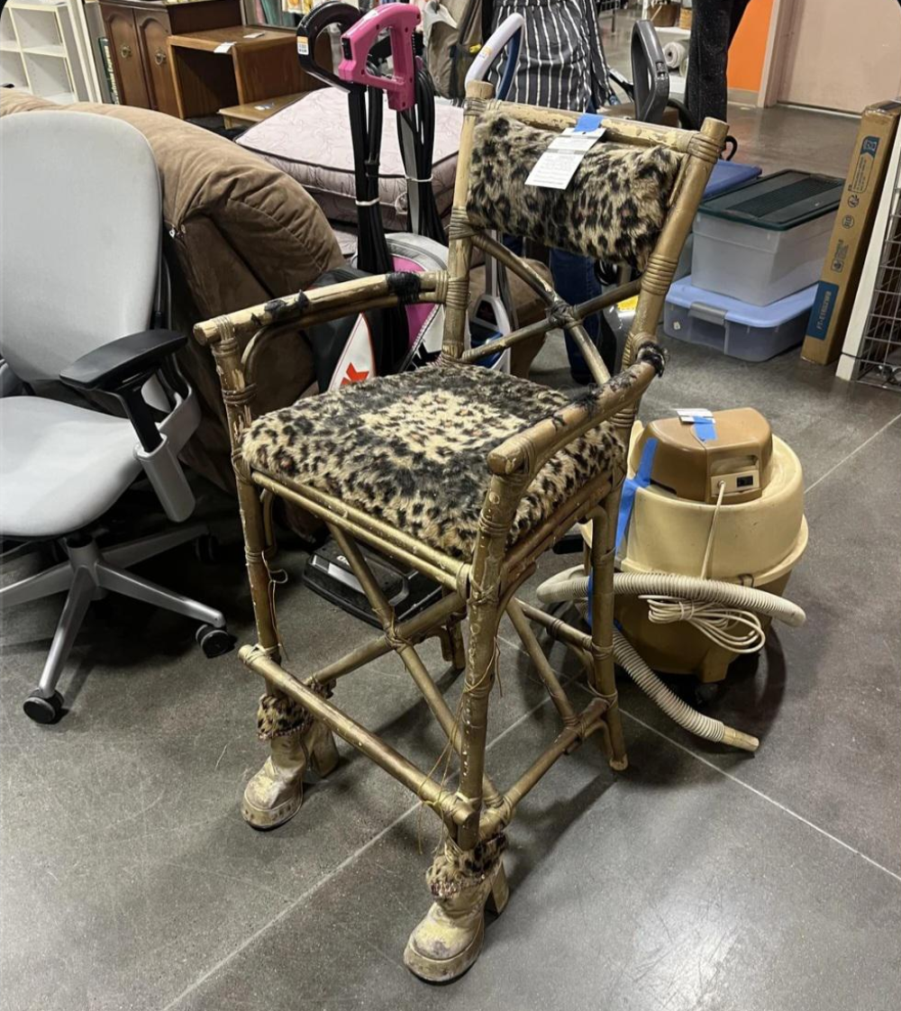 A bamboo bar stool with leopard print upholstery and platform shoes attached to the base of the legs.