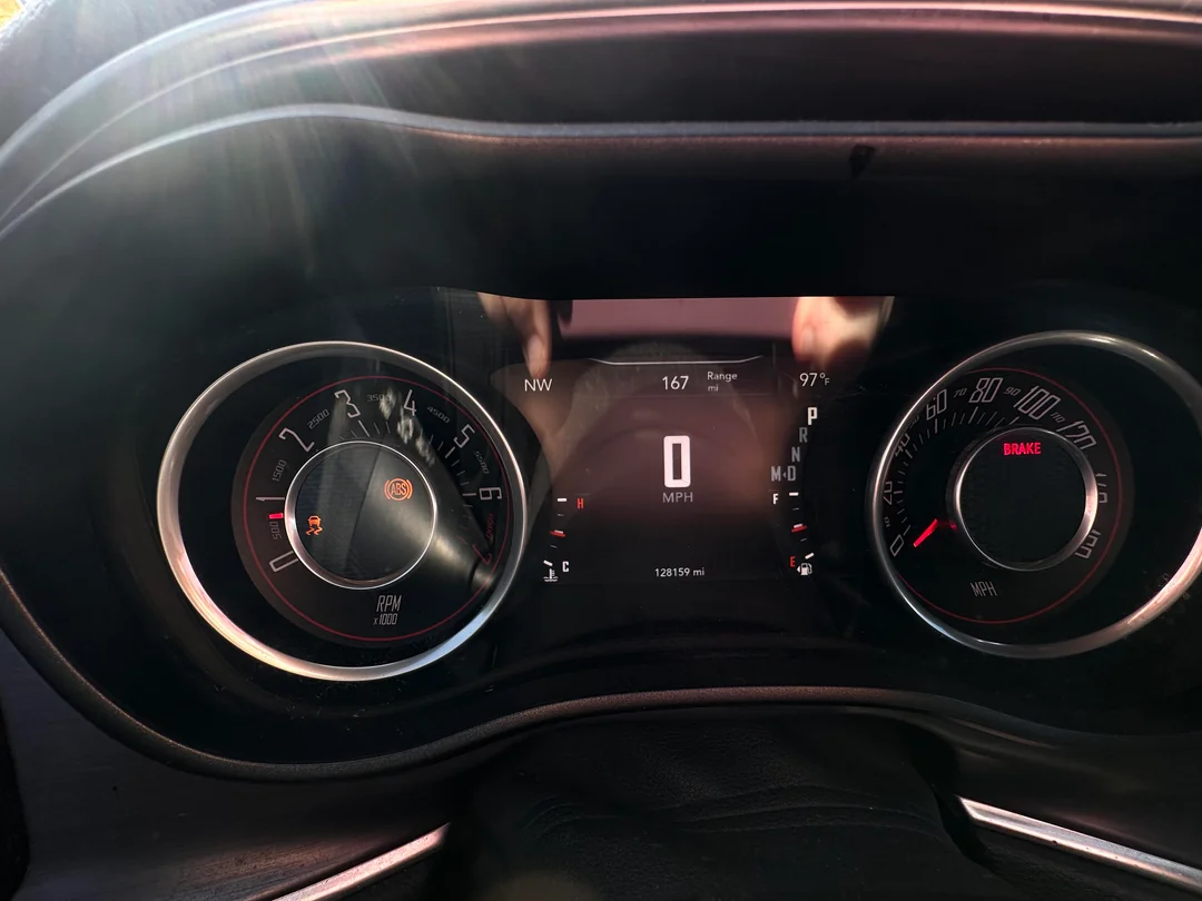 A car dashboard showing 0 MPH, 128,159 miles, and illuminated ABS and brake warning lights.