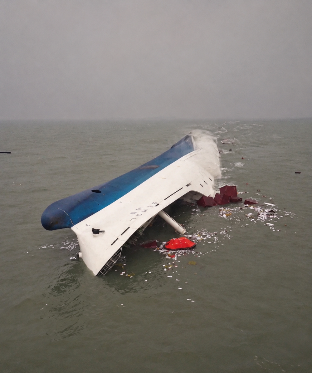 The ferry Sewol capsized and partially submerged in the ocean, with debris floating nearby.