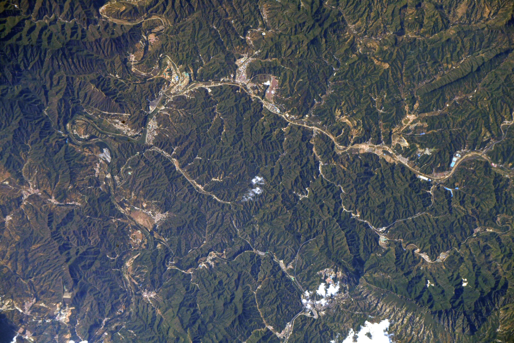 Aerial view of a mountain range with winding roads and small settlements nestled in the valleys.