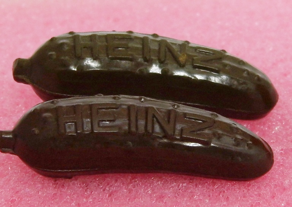 Two dark brown, pickle-shaped charms embossed with the Heinz logo.