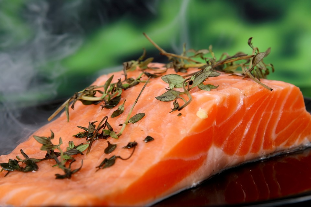 A fresh salmon fillet topped with herbs and wisps of steam.