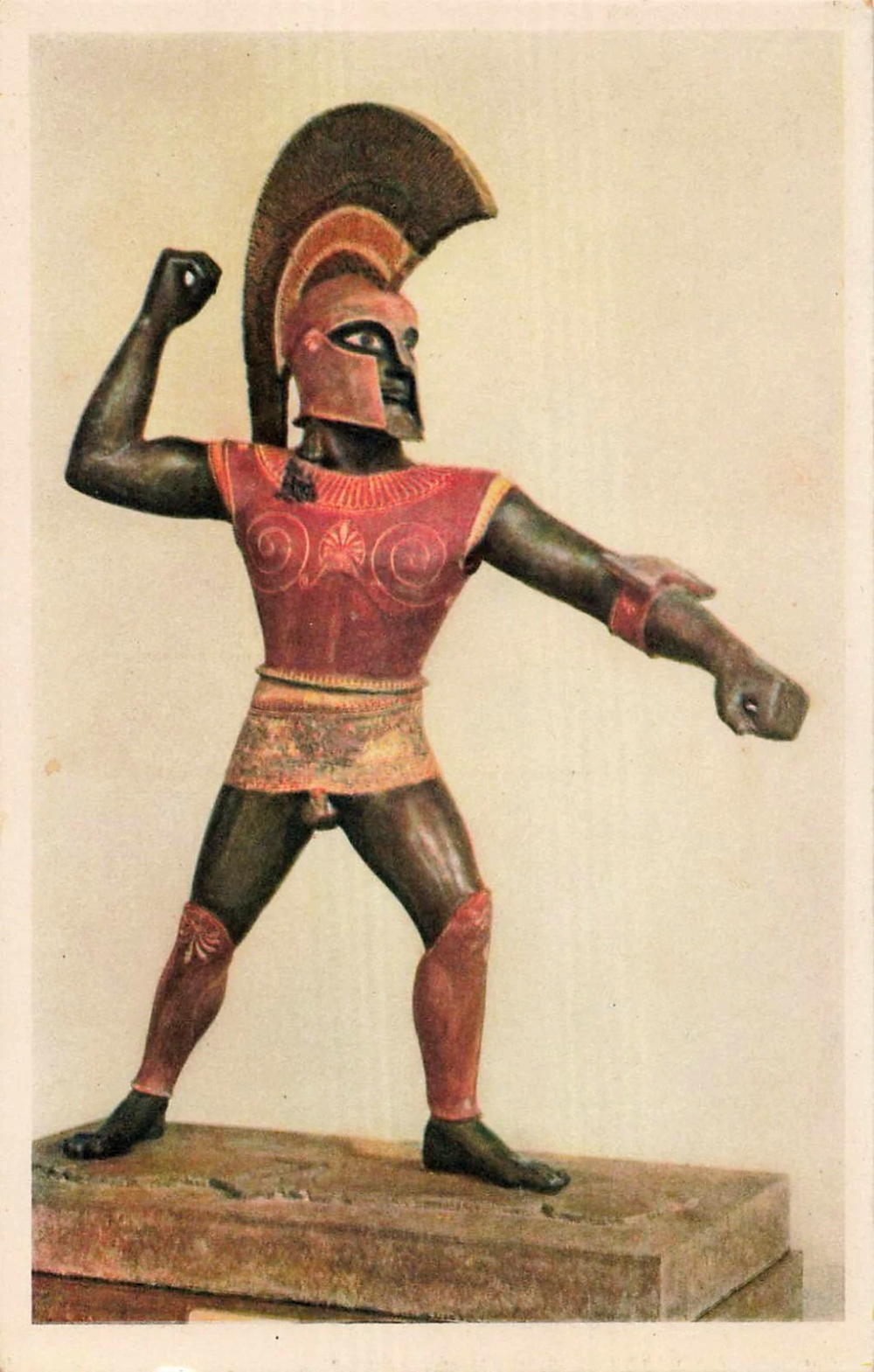 Bronze statue of a warrior wearing a crested helmet and breastplate, posed with one arm raised as if to strike.