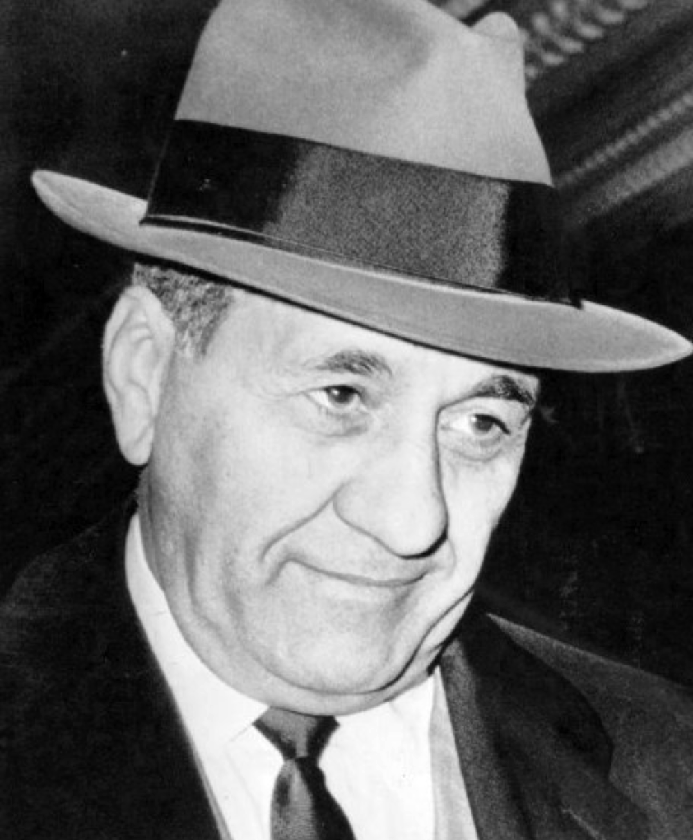 Black and white portrait of a man wearing a fedora, suit, and tie.