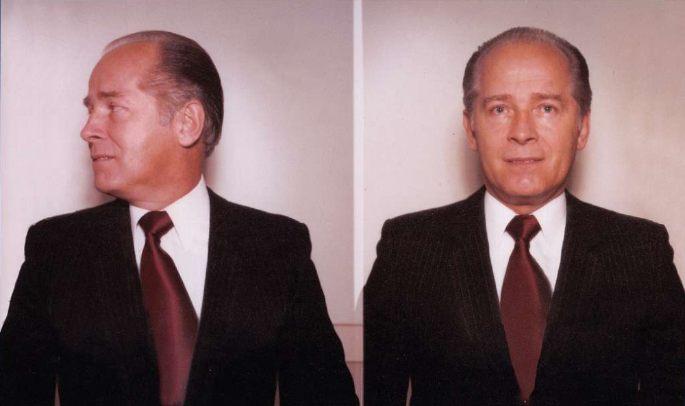 A split-screen portrait of a man in a dark suit and red tie, showing him in profile on the left and facing forward on the right.