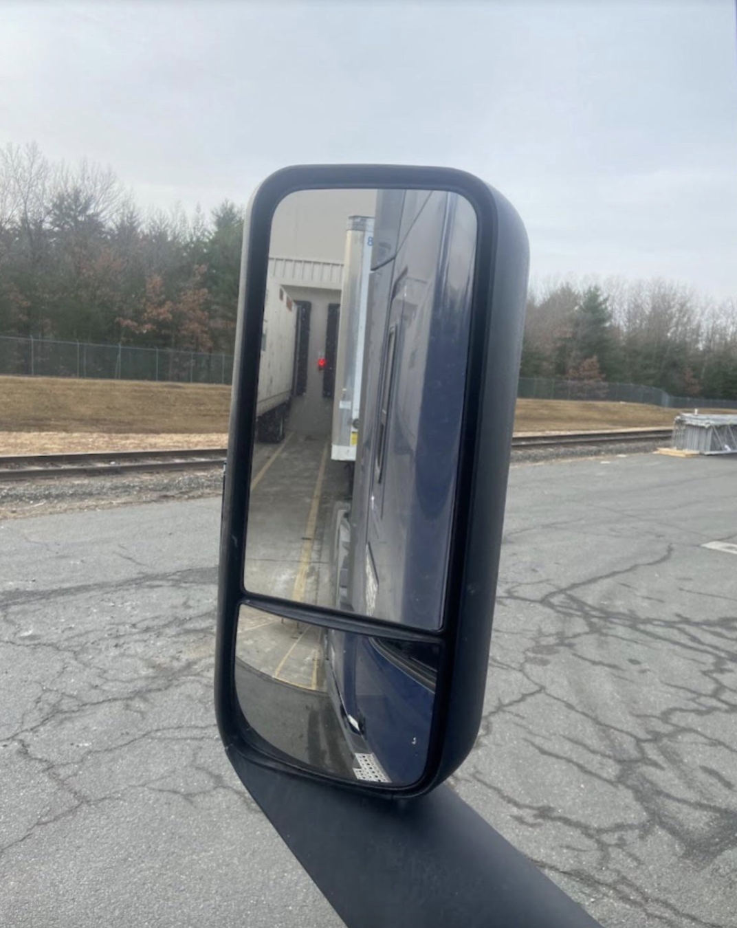 View from a truck side mirror showing the vehicle reversing toward a loading dock.