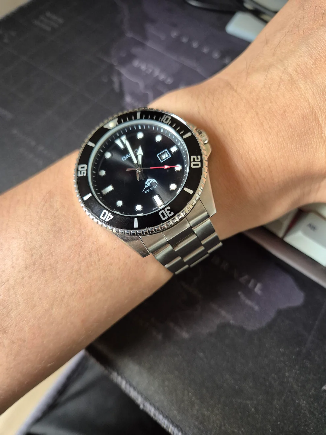 A Casio Duro dive watch with a black dial and steel bracelet on a person’s wrist.