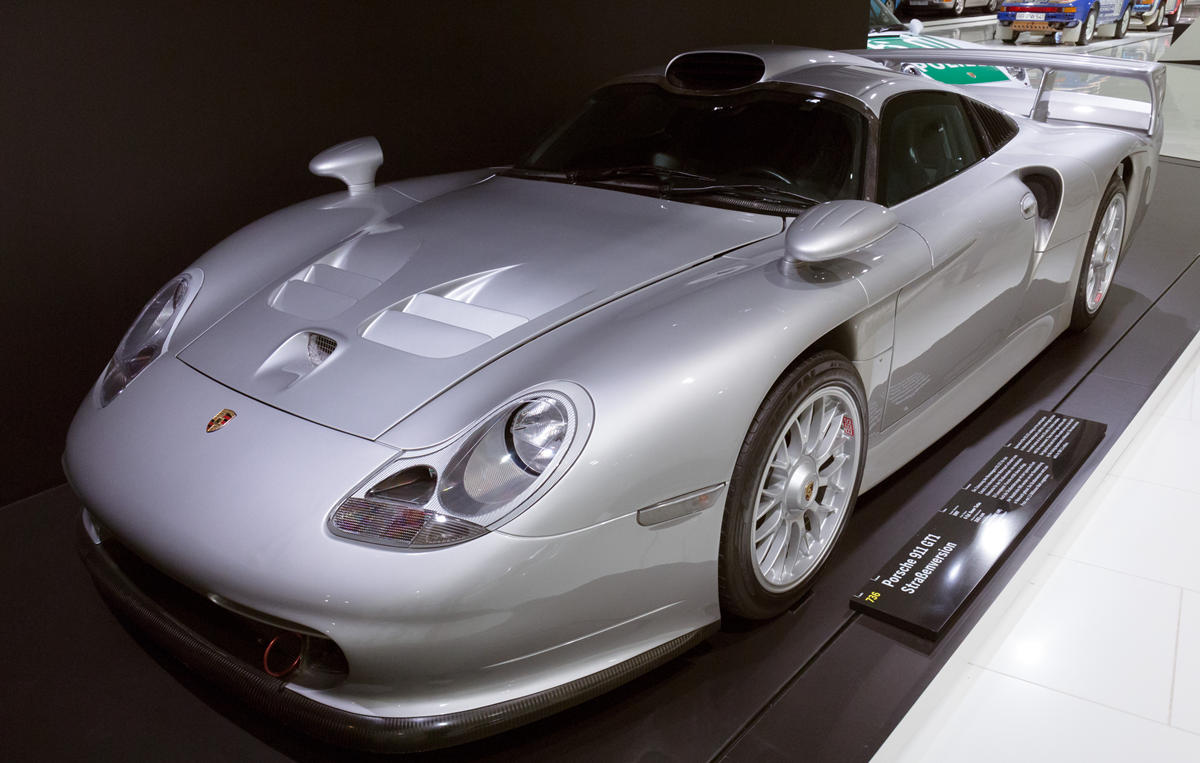 Silver Porsche 911 GT1 Straßenversion sports car on display in a museum.