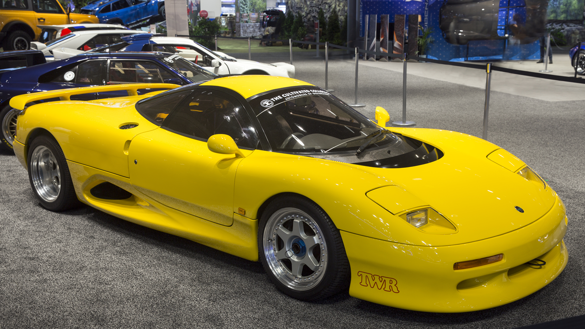 A bright yellow Jaguar XJ220 sports car on display at an indoor car show.