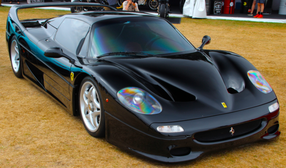 Black Ferrari F50 parked on a grassy field.