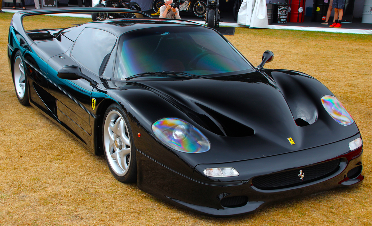 Black Ferrari F50 parked on a grassy field.