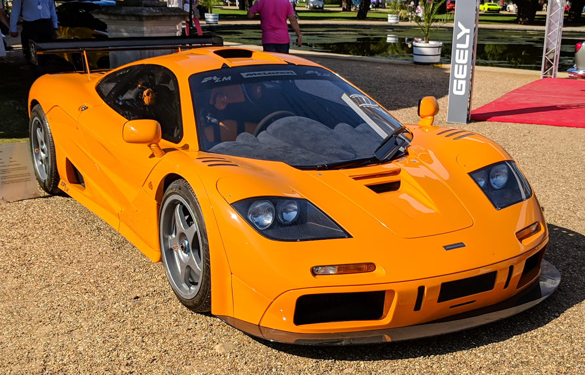 Bright orange McLaren F1 GTR parked on a gravel path.