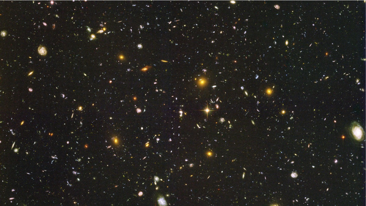 A vast field of deep space filled with numerous galaxies and stars of varying sizes and brightness.