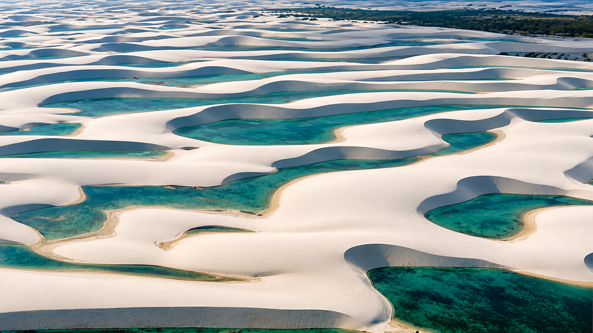 Natural. Aerial view of white sand dunes interspersed with turquoise rainwater lagoons in Lençóis Maranhenses National Park.