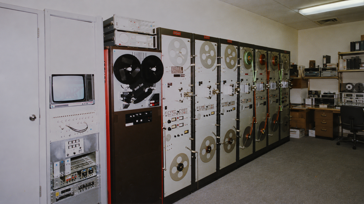 A row of vintage reel-to-reel magnetic tape data storage units in a server room.