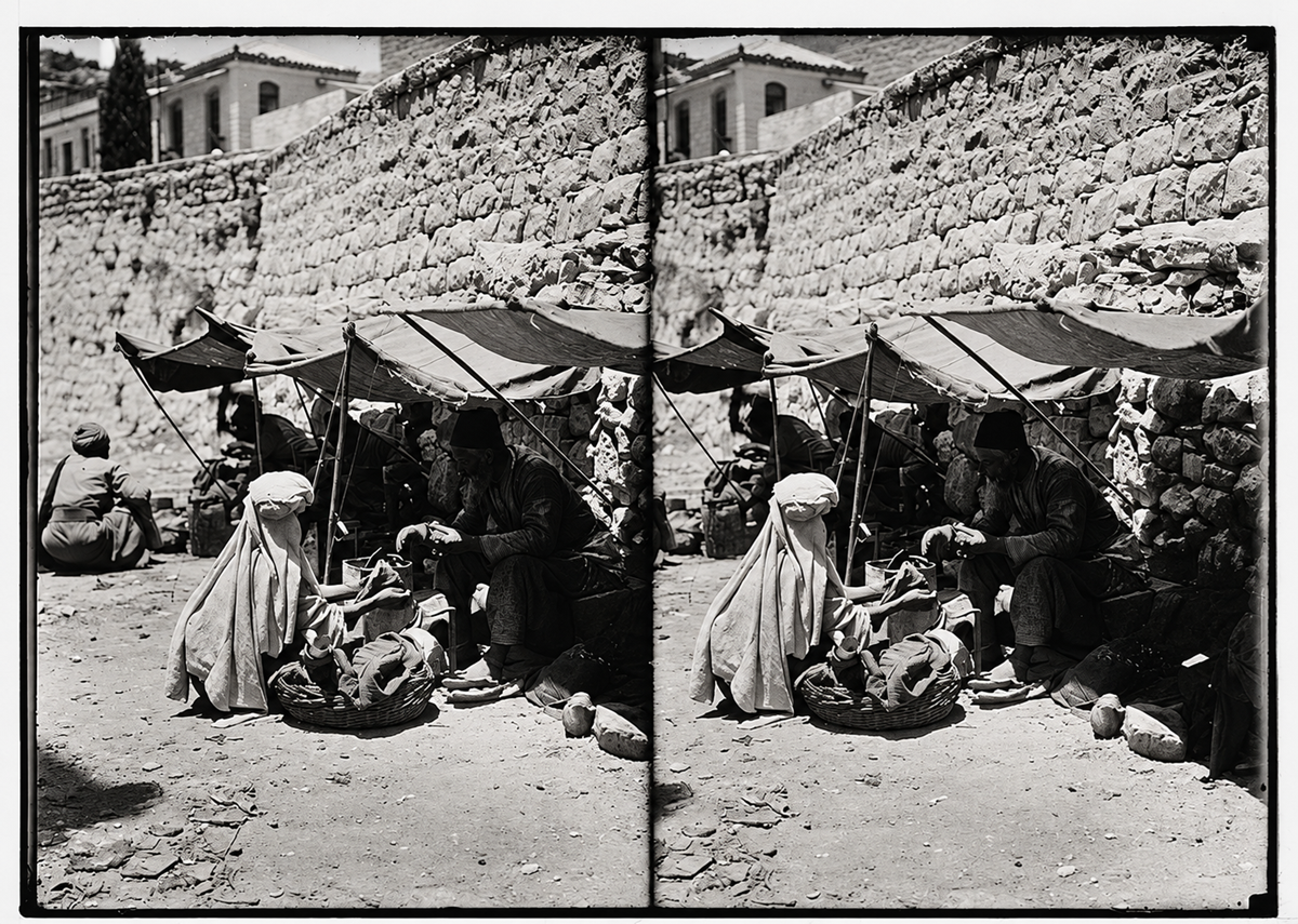Stereoscopic view of two people sitting on the ground beneath sunshades, tending to baskets against a stone wall.