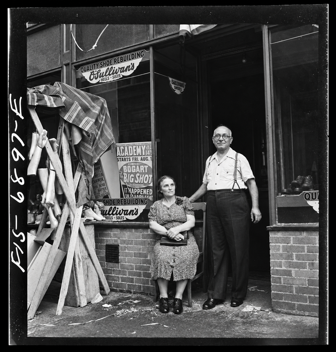 A man and woman stand outside a shop entrance, with a display of mannequin legs on the left and a movie poster for “Big Shot” in the window.