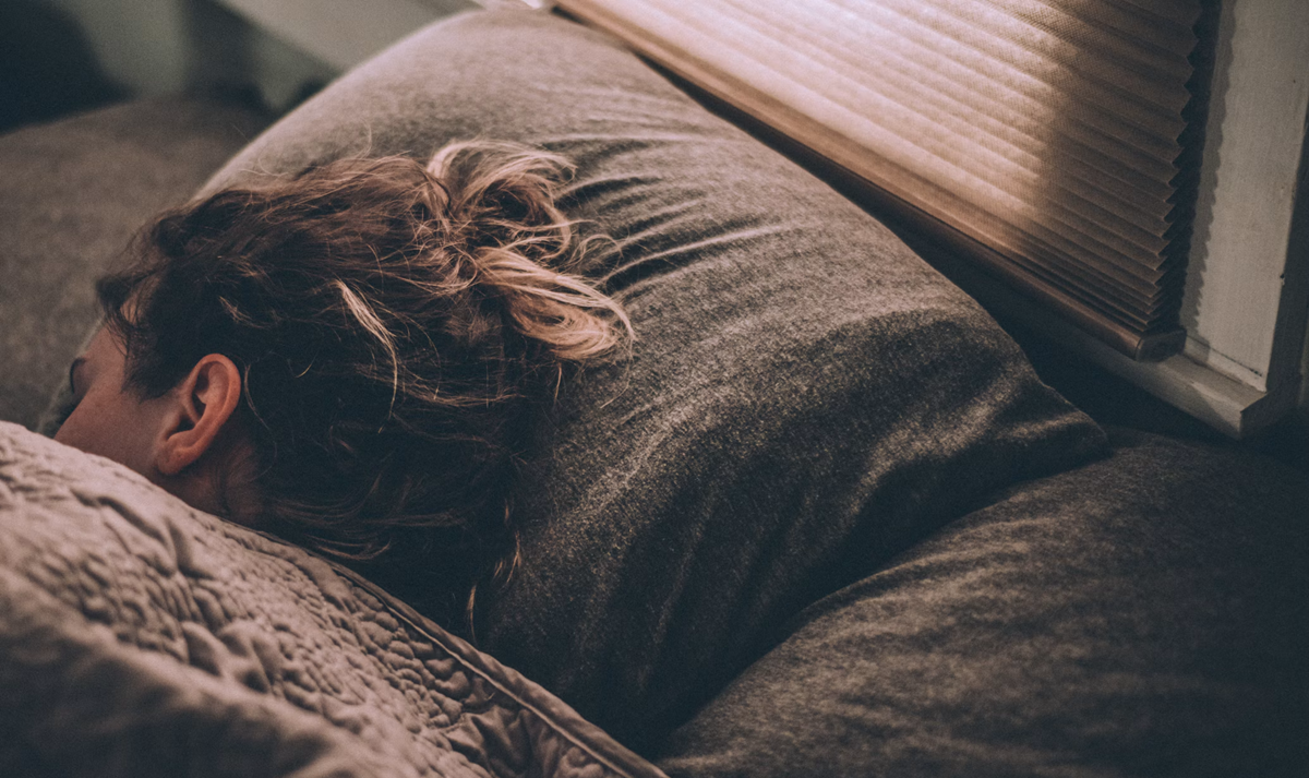 A person sleeping on a pillow with their face turned away.