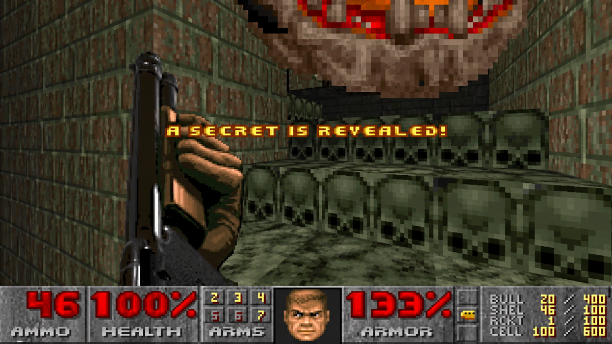 First-person view of the game Doom with a shotgun held in the foreground, displaying the text “A secret is revealed!” over a brick room decorated with skull motifs.