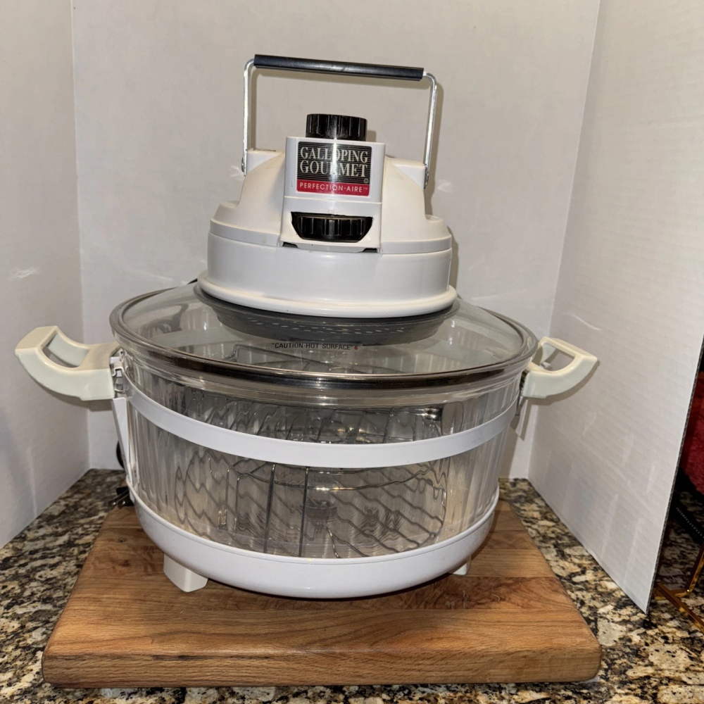Galloping Gourmet brand convection oven with a glass bowl and white base sitting on a wooden cutting board.