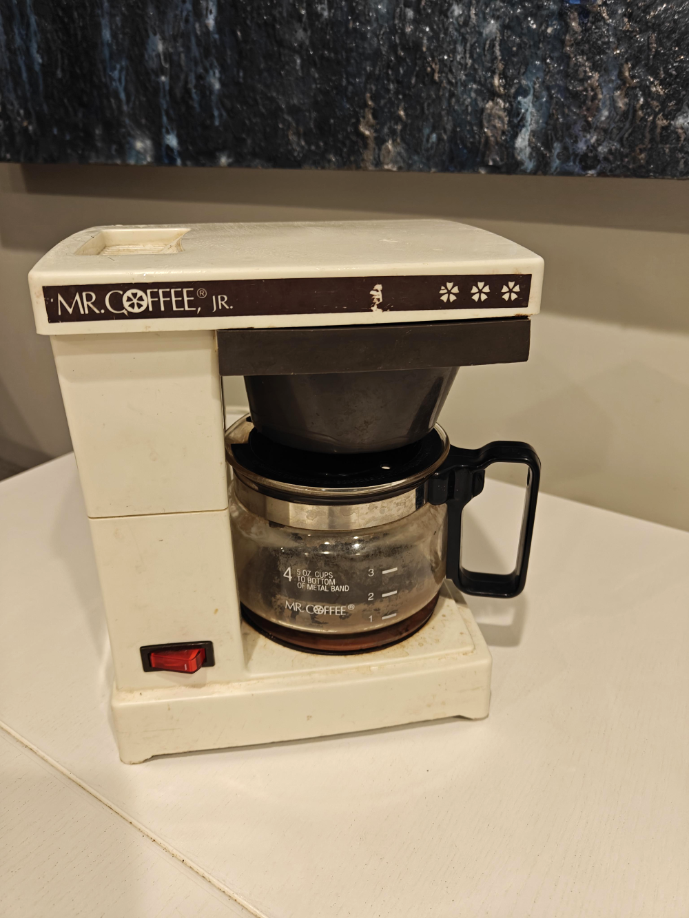 A vintage off-white Mr. Coffee Jr. drip coffee maker with a glass carafe.