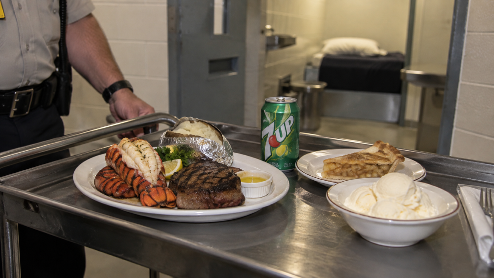 A food tray on a metal cart featuring a lobster tail, steak, baked potato, a can of 7-Up, a slice of apple pie, and a bowl of vanilla ice cream, with a prison cell in the background.
