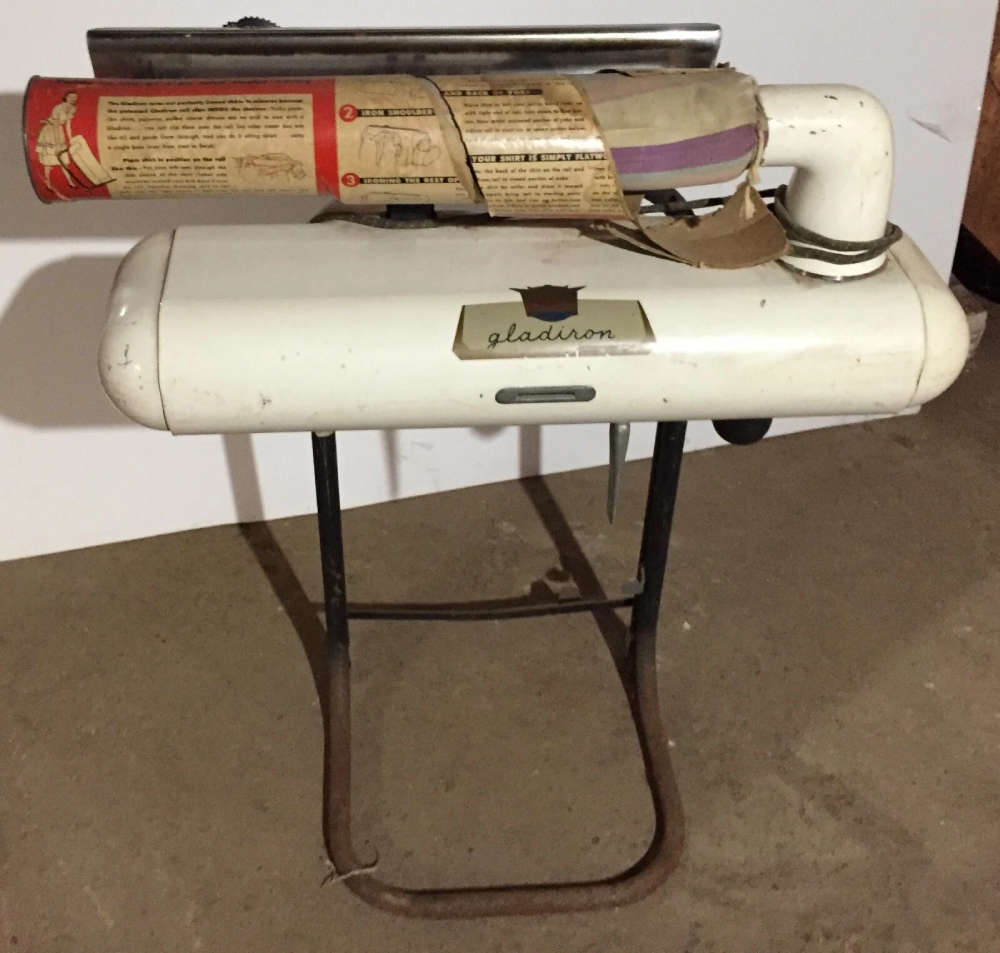 A vintage Gladiron rotary iron with a metal stand and an original instructional paper label attached to the top roller.