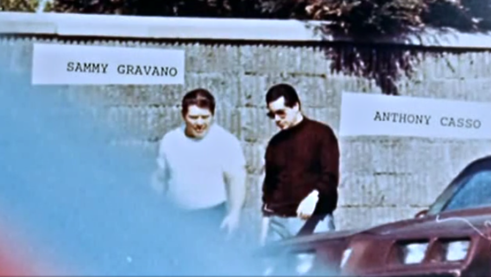 A vintage photograph of Sammy Gravano and Anthony Casso standing in front of a wall, with their names labeled above them.