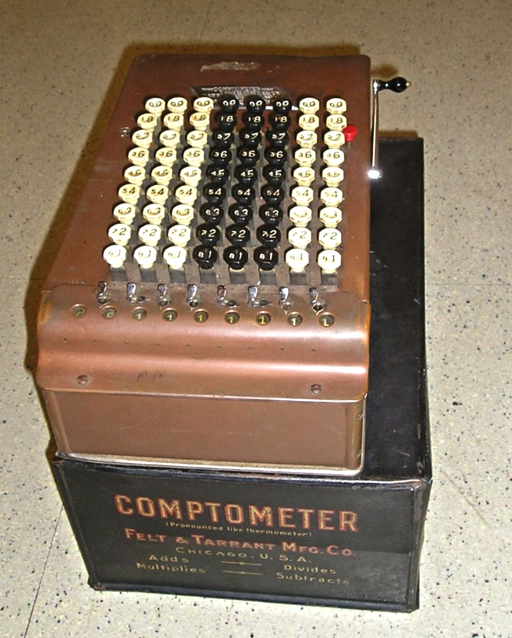 Vintage Comptometer adding machine with a grid of numbered keys, mounted on a black base labeled with the manufacturer name and location.