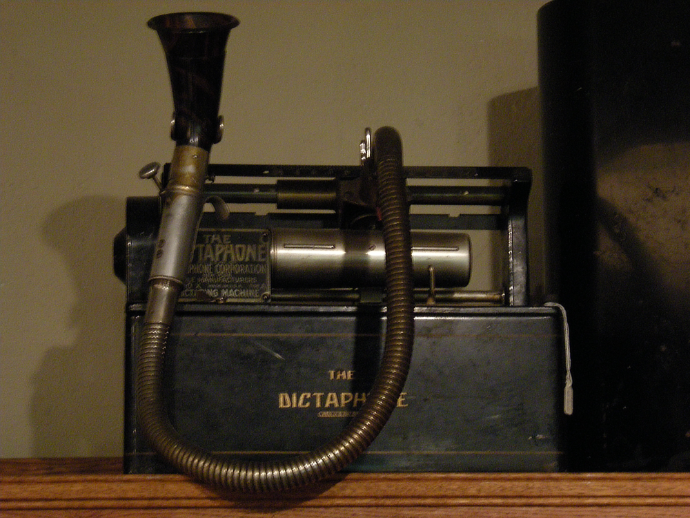 An antique Dictaphone recording machine with a prominent flexible metal speaking tube.