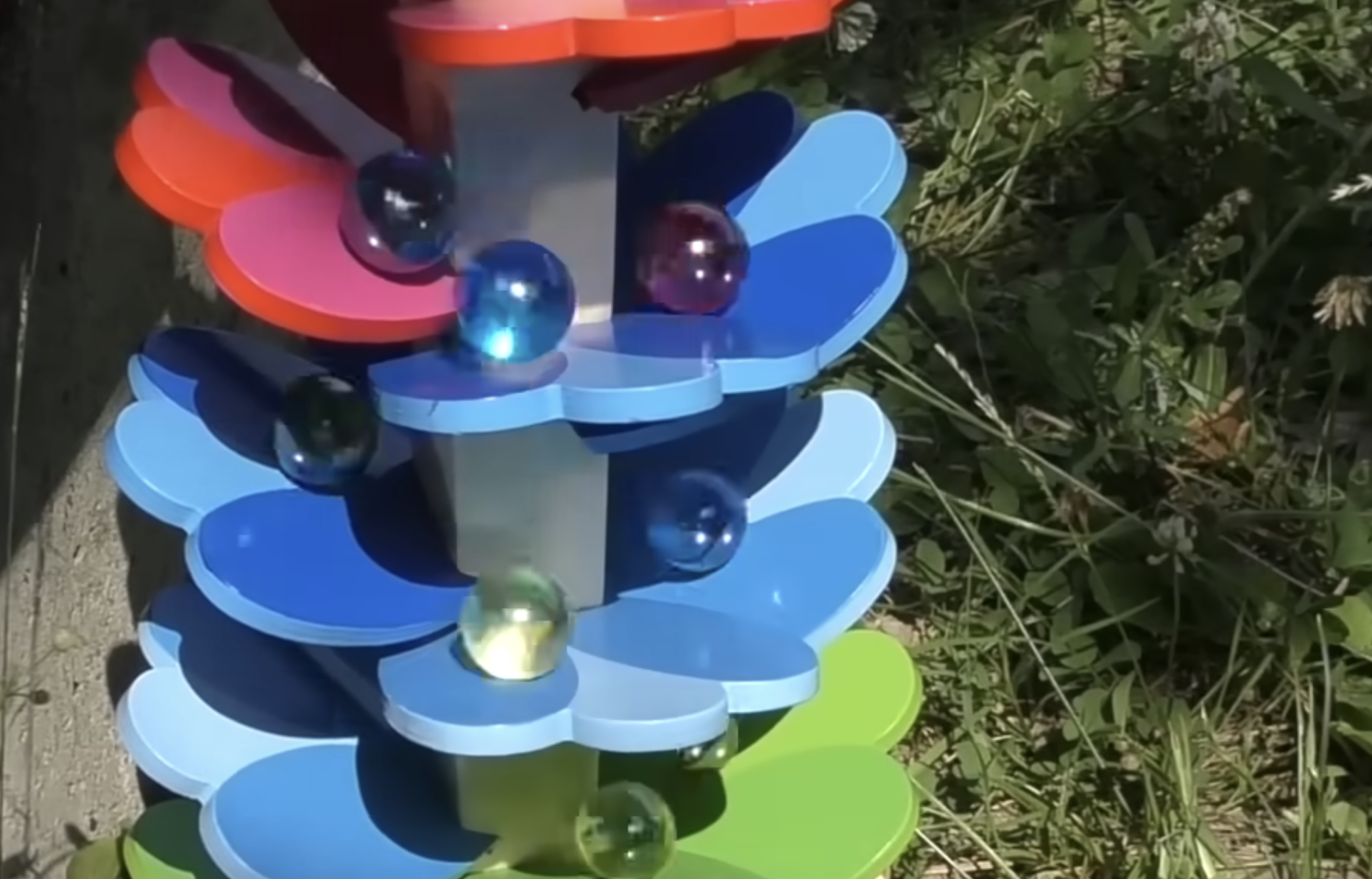 Marbles roll down a multi-colored, flower-shaped tiered tower.