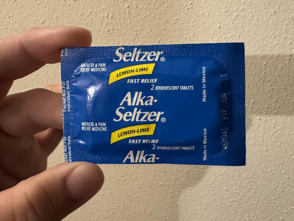 A blue packet of lemon-lime Alka-Seltzer effervescent tablets held by a hand.