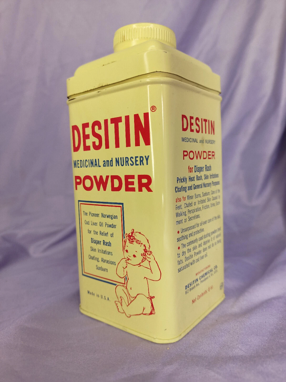 A yellow vintage metal container of Desitin Medicinal and Nursery Powder with a red illustrated baby logo and product information printed on the front.