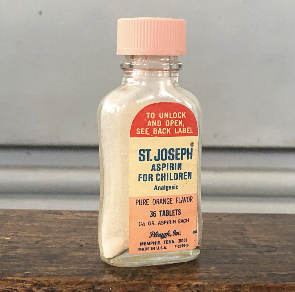 Vintage glass bottle of St. Joseph Aspirin for Children with a pink cap and a label indicating 36 orange-flavored tablets.