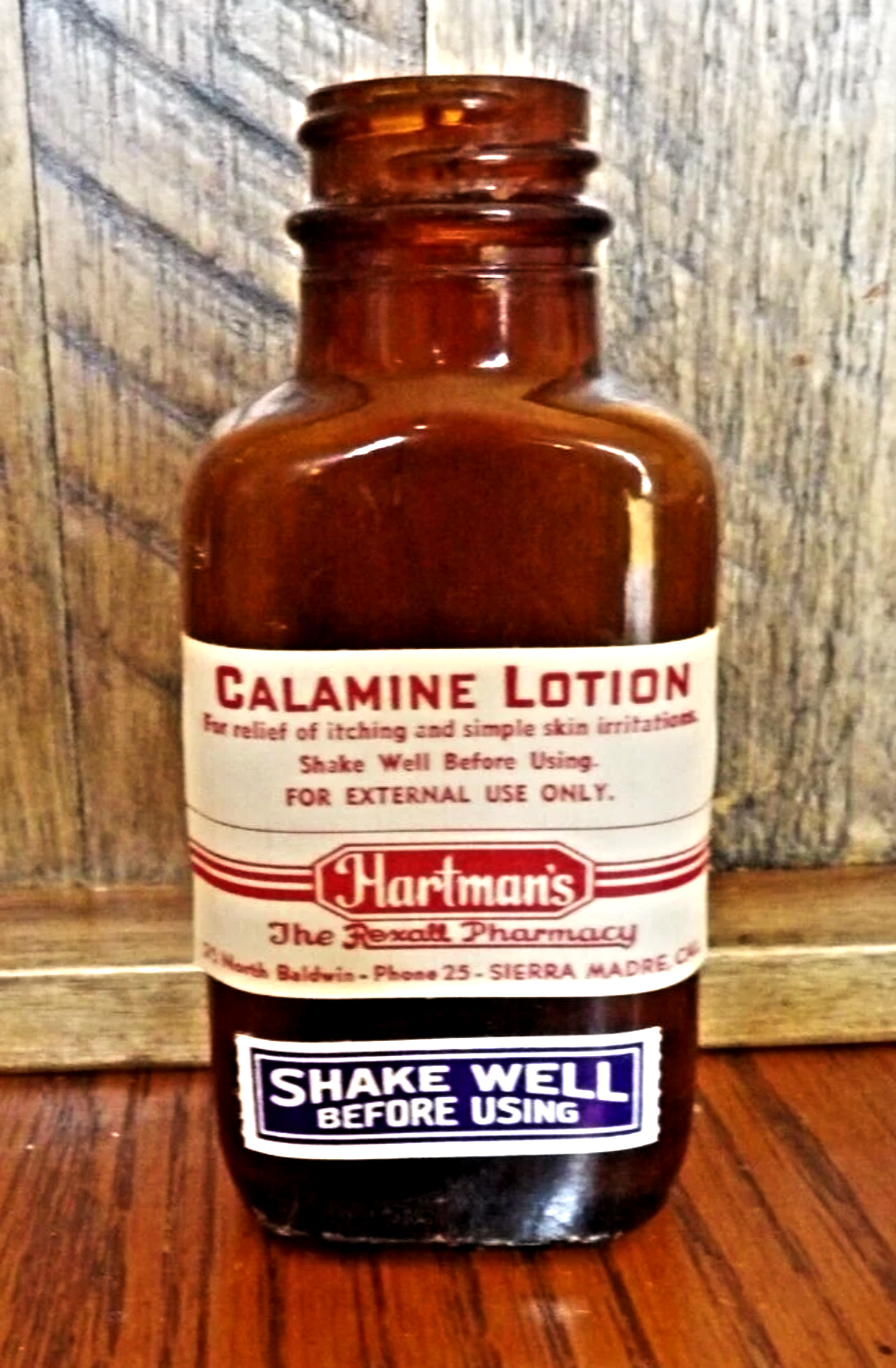 Vintage amber glass bottle of Hartman’s Calamine Lotion with a white paper label.