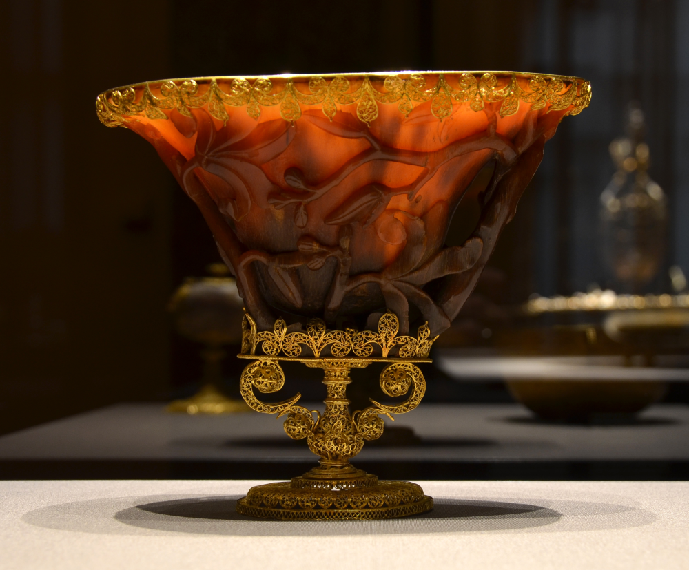 A carved amber bowl with ornate gold filigree trim and base.