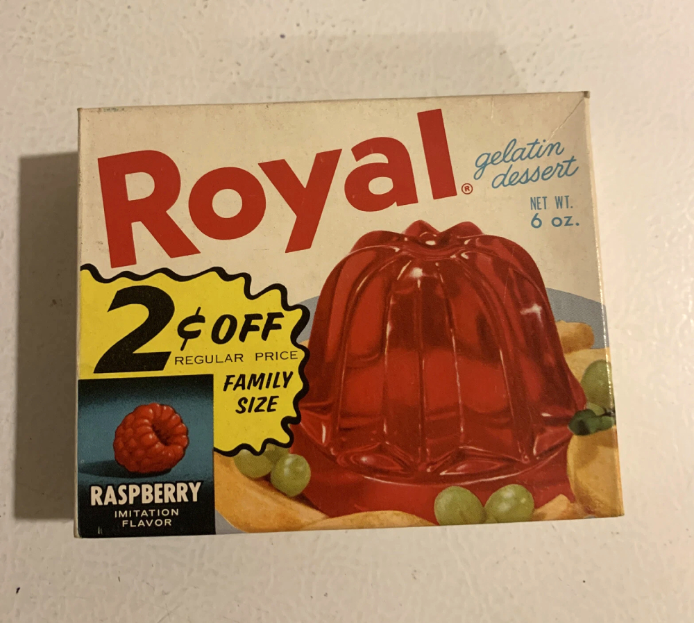 A box of Royal Raspberry imitation flavor gelatin dessert, featuring a 2 cents off promotional sticker and an image of a molded red gelatin dessert surrounded by grapes.