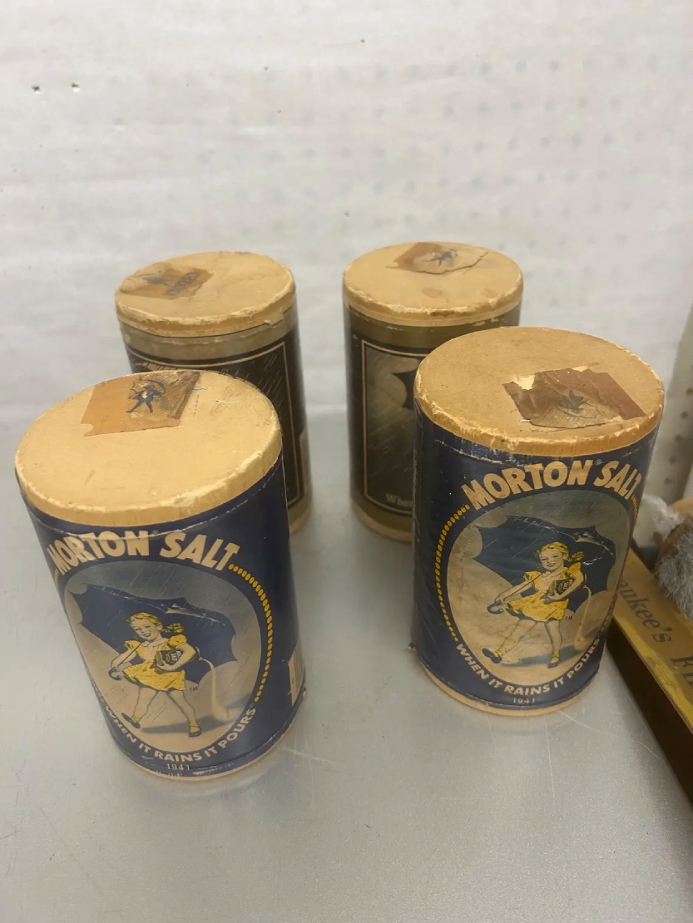 Two vintage Morton Salt canisters with yellow lids, each featuring the classic illustration of a girl in a yellow dress holding an umbrella.