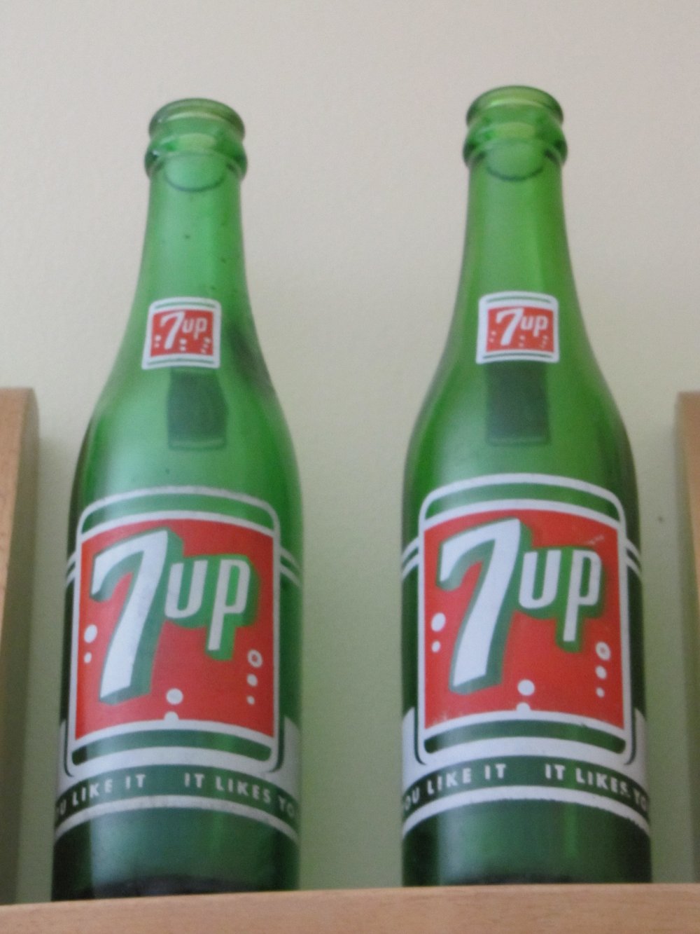 Two vintage green glass 7up soda bottles standing side by side.