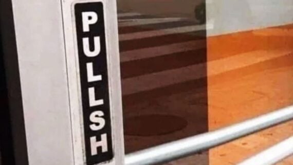 A vertical sign on a door with the word “PULLSH” printed in white letters on a black background.