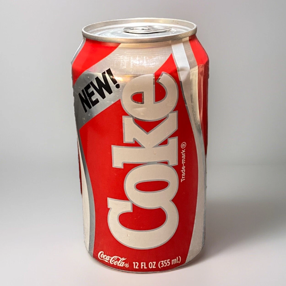 A dented 12-ounce can of New Coke with its classic red and white branding.