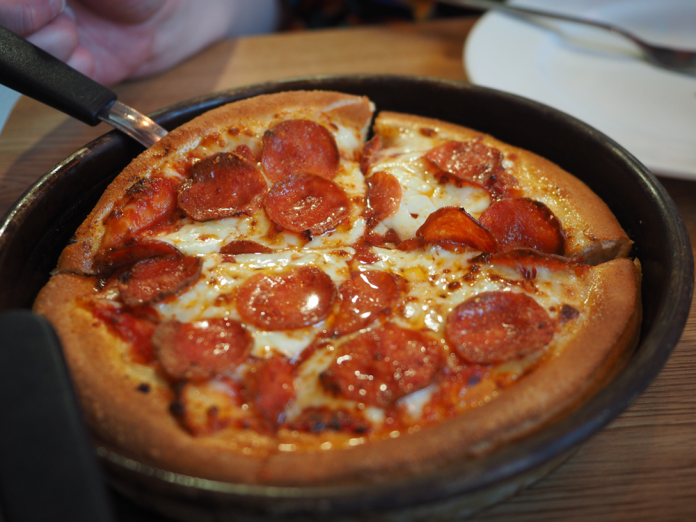 A personal pan pepperoni pizza sliced into four pieces in a black skillet.